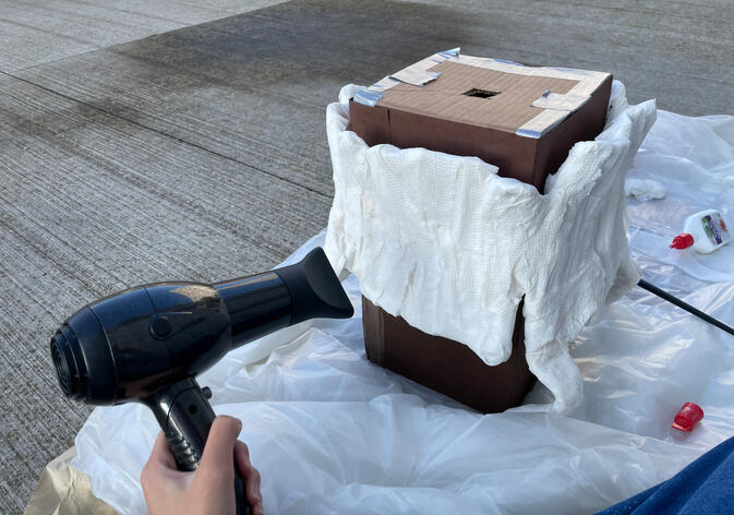 Creating a paper mache "tree trunk" around the cardboard base.